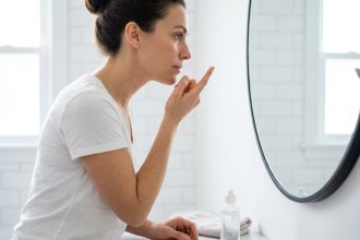 Femme insérant une lentille de contact devant un miroir de salle de bain, illustrant les habitudes quotidiennes avec les lentilles